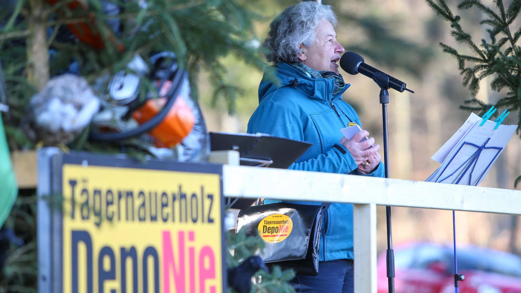 Eine Frau spricht an einer Demonstration in einem Wald ins Mikrofon.