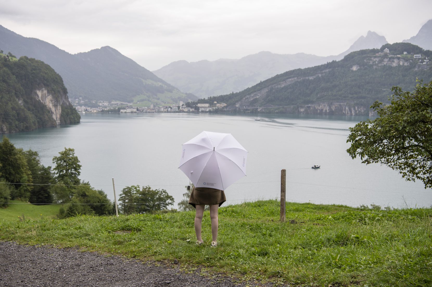 Eine Besucherin mit Regenschirm blickt auf den Vierwaldstaettersee anlaesslich der Bundesfeier auf dem Ruetli, welche im Zeichen der Schweizer Jugend steht, am Dienstag, 1. August 2023. 