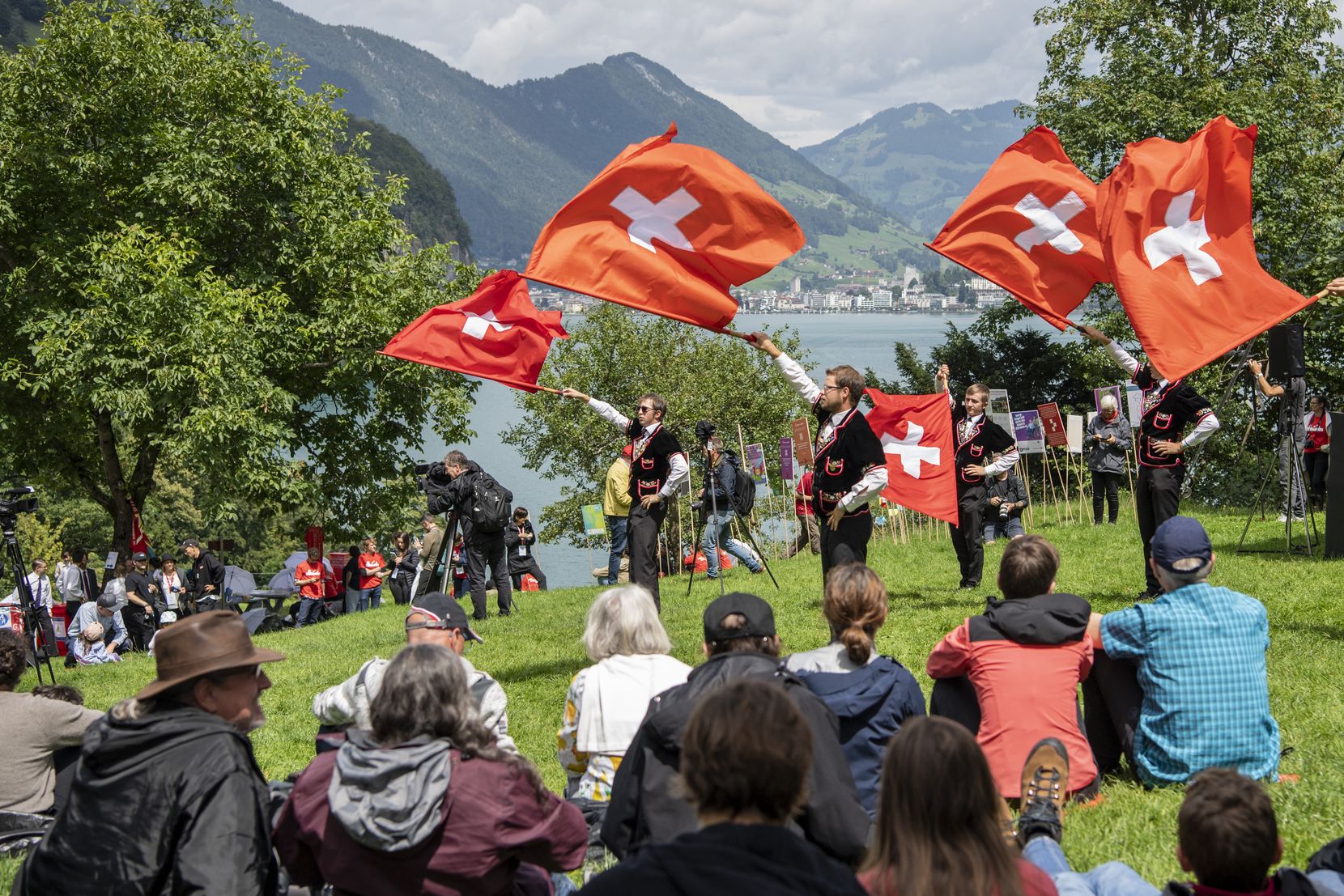 Männer in Kostümen schwingen die Schweizer Fahne.