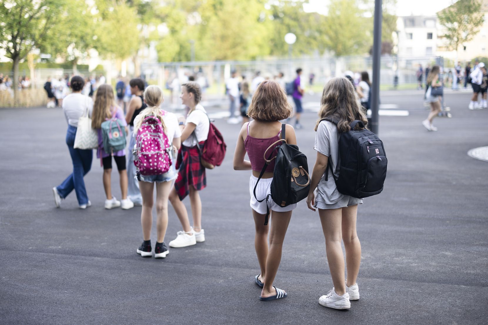 Jugendliche warten am ersten Schultag auf dem Pausenplatz.
