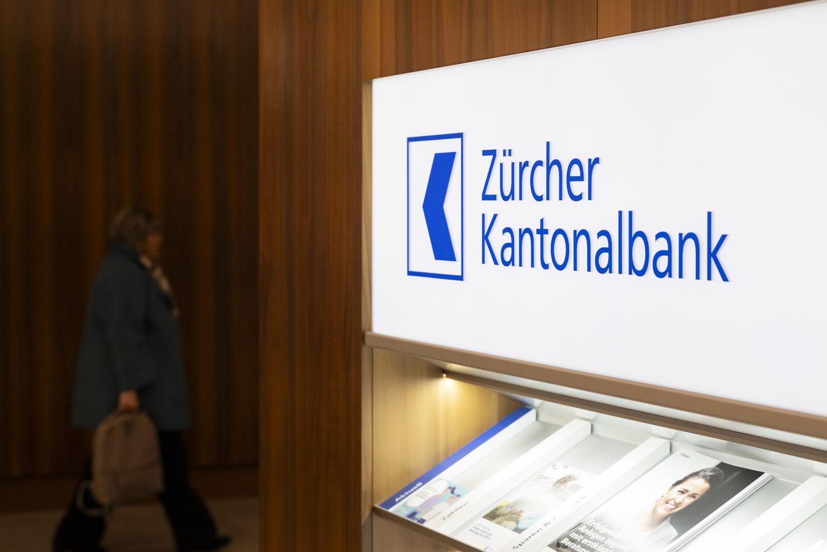 Das Logo der Zürcher Kantonalbank über einer Auslage mit verschiedenen Publikationen der Bank.