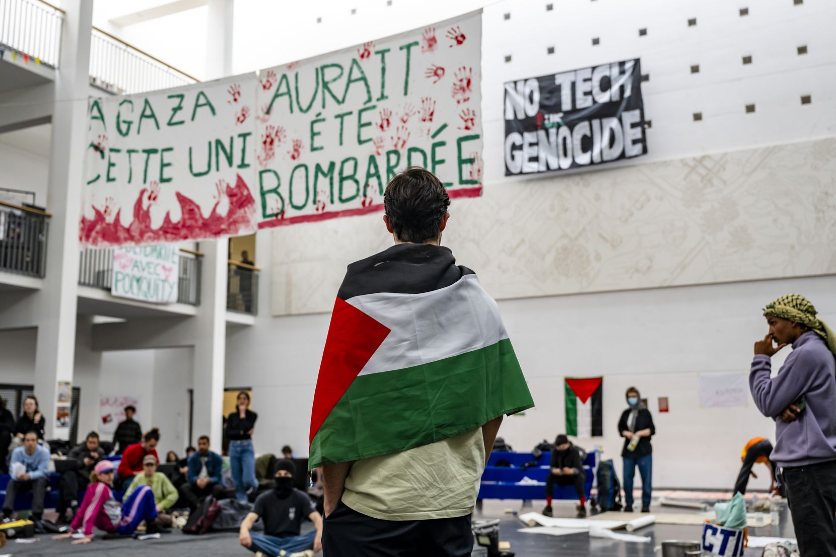 Protestierende an der EPFL in Lausanne. Im Vordergrund ein Mann in eine Palästina-Flagge gehüllt.