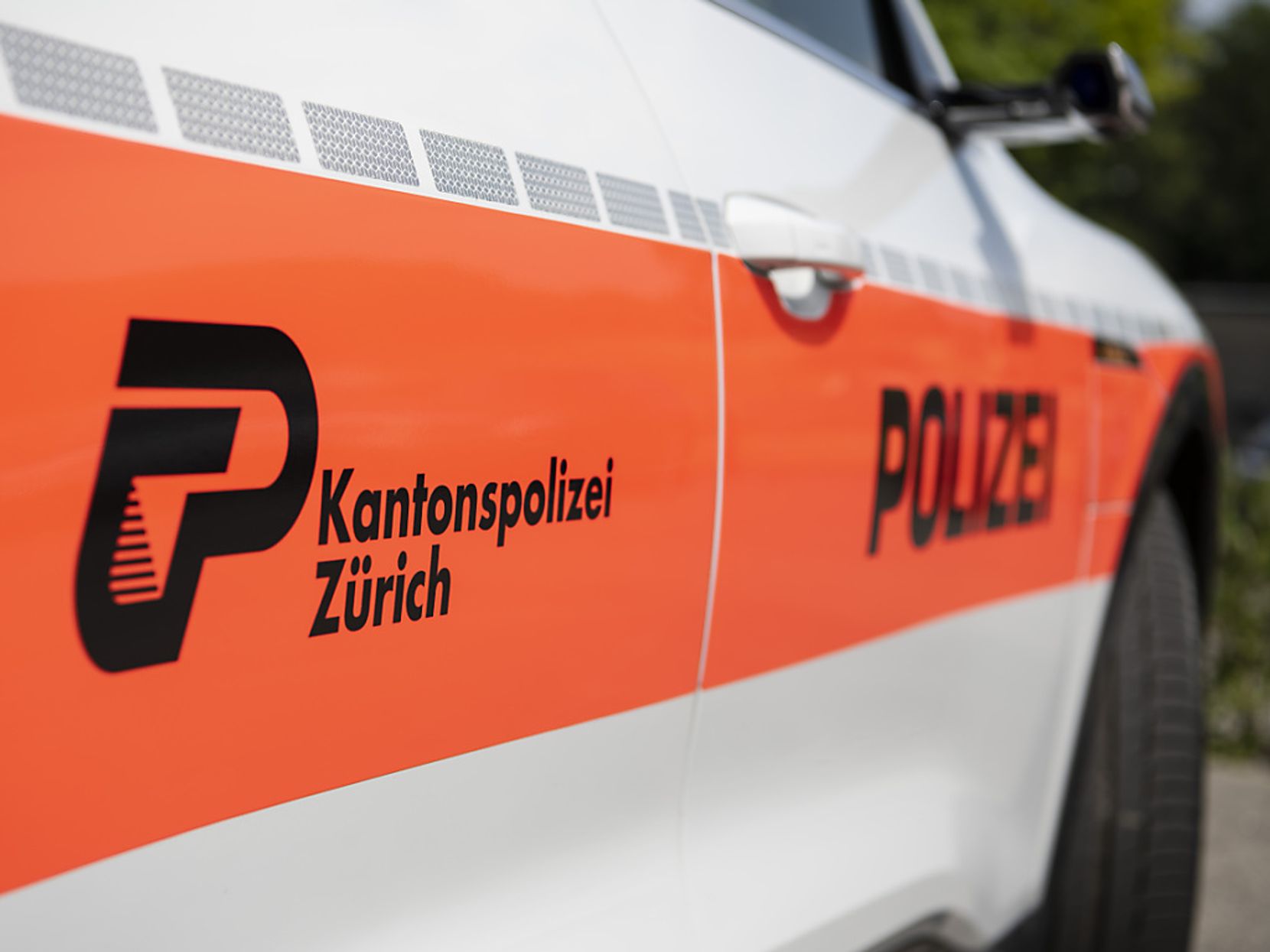 Weiss-oranger Polizeiwagen mit Aufschrift Kantonspolizei Zürich.