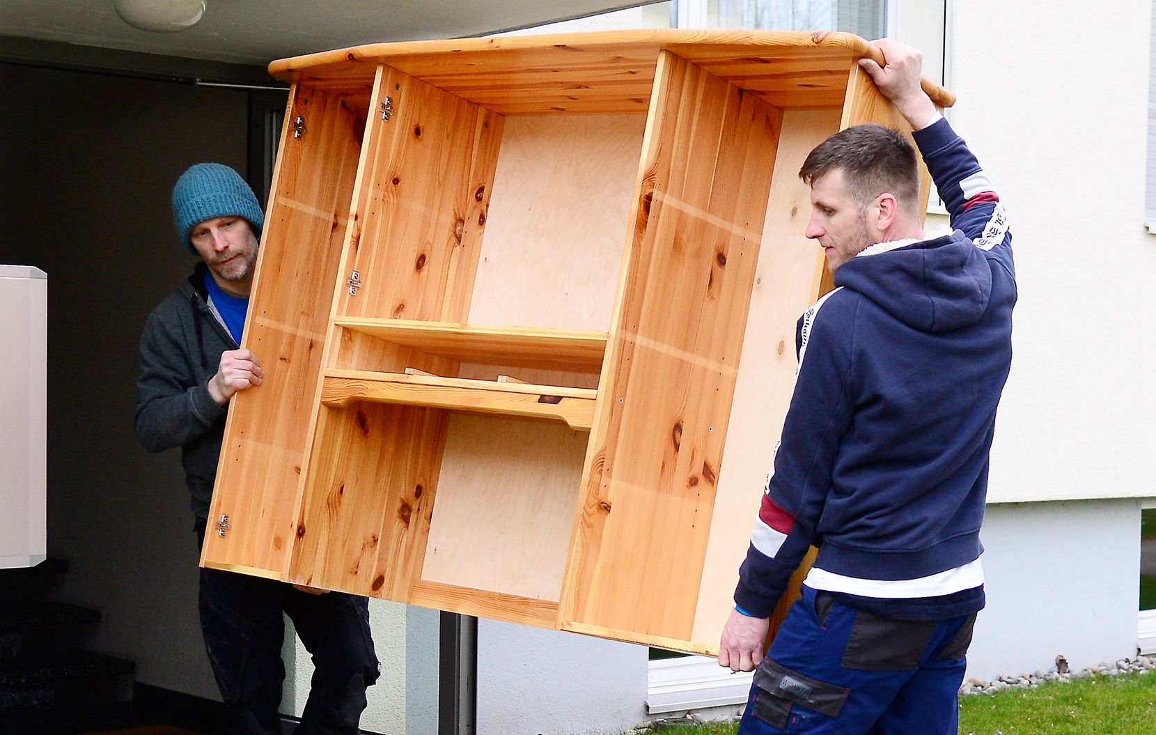 Michael Plancherel und sein  und sein ukrainischer Helfer Illya Nuzhdow tragen ein Holzmöbel aus dem Haus.
